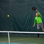 Older man in a green shirt playing pickleball at Guilford Racquet & Swim Club