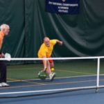 Man in yellow playing pickleball indoors at Guilford Racquet & Swim Club