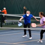 Man in blue shirt wearing a facemask as he plays pickleball