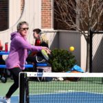 Woman wearing a light purple hoodie playing pickleball outdoors